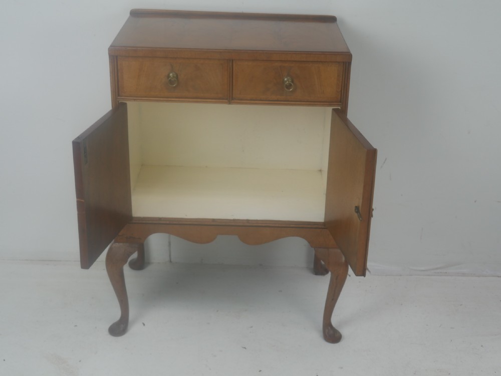 A Queen Anne revival walnut bedside cabinet featuring two top drawers, a two-door cupboard, and tall cabriole legs. View IX