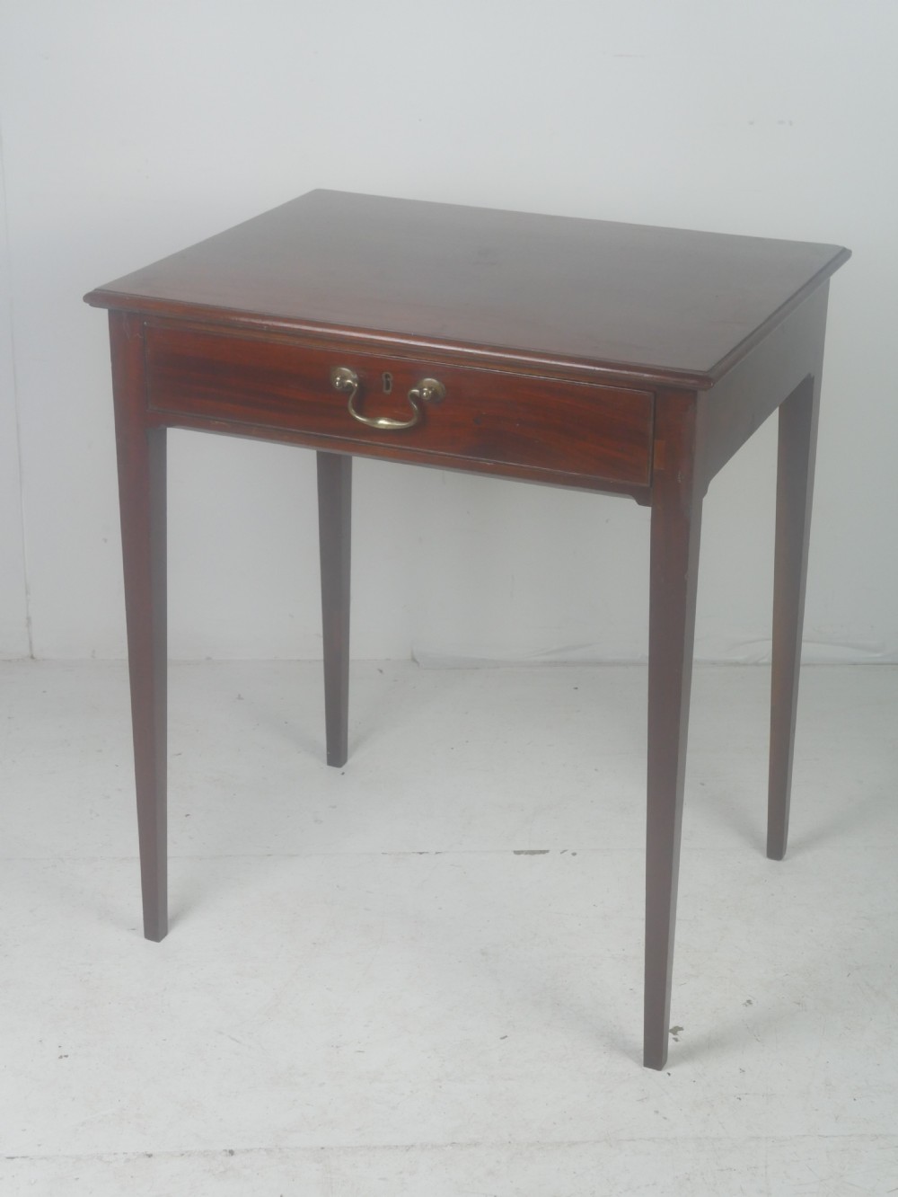 A rectangular mahogany lamp table with straight tapered legs and a single drawer featuring a brass drop handle.