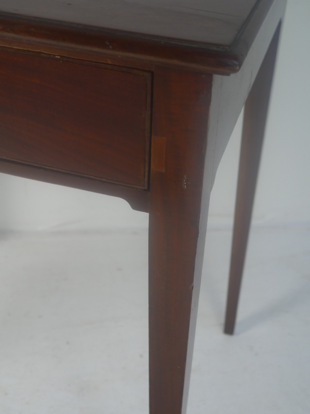 A rectangular mahogany lamp table with straight tapered legs and a single drawer featuring a brass drop handle. View X
