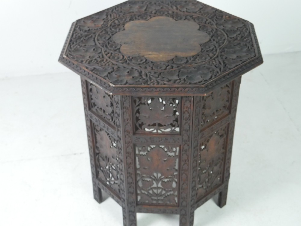 An octagonal dark wood side table featuring hand-carved foliage fretwork on all side panels and a relief carved top. View III