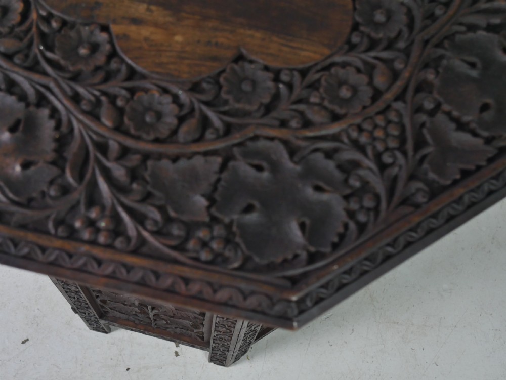 An octagonal dark wood side table featuring hand-carved foliage fretwork on all side panels and a relief carved top. View V