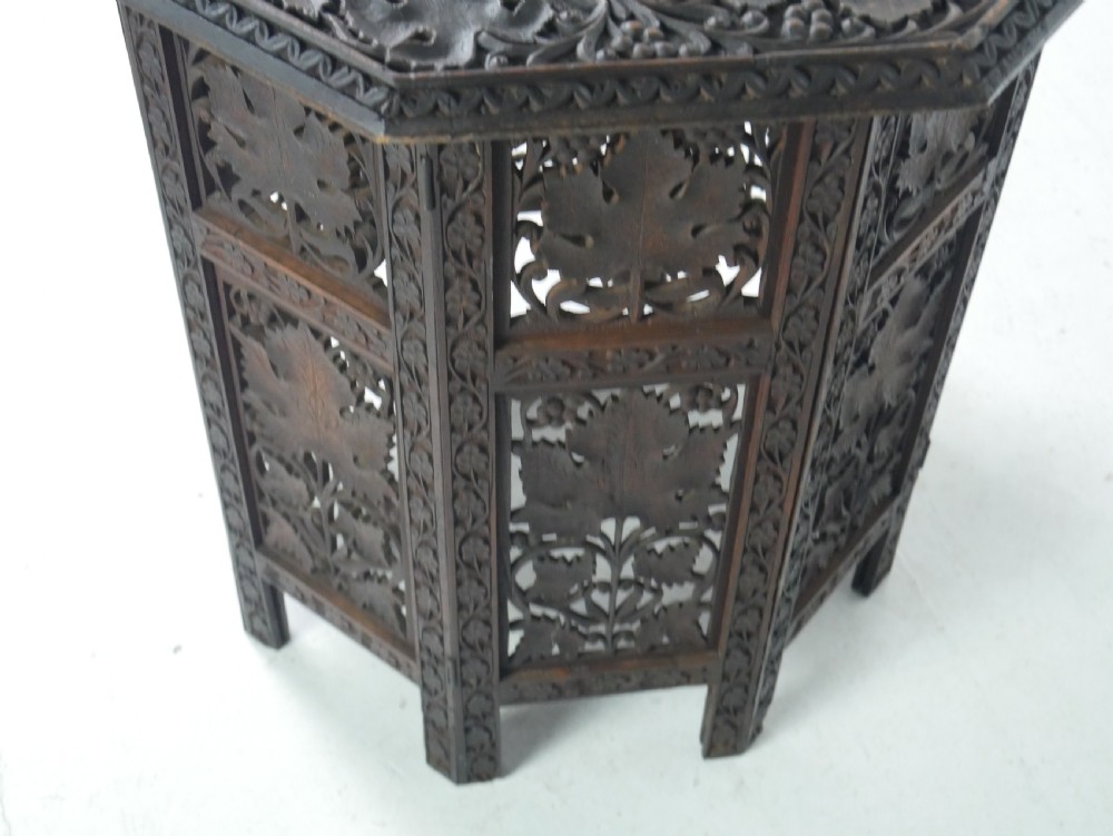 An octagonal dark wood side table featuring hand-carved foliage fretwork on all side panels and a relief carved top. View VI