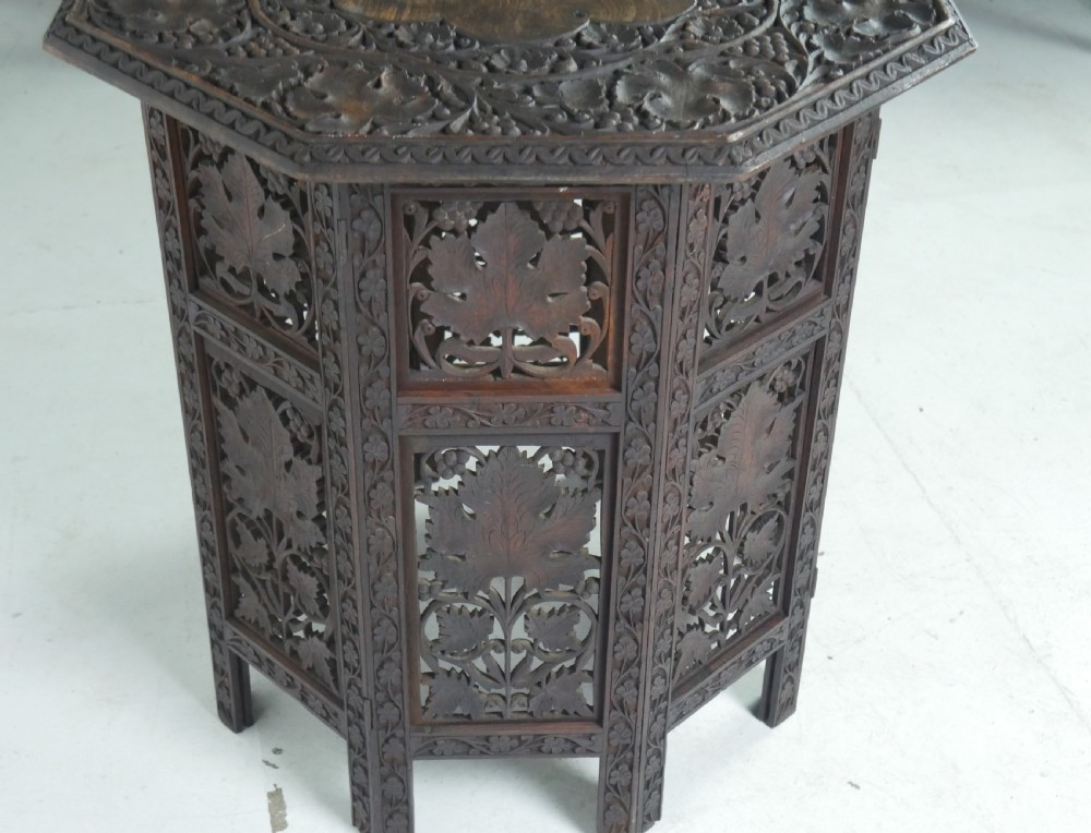 An octagonal dark wood side table featuring hand-carved foliage fretwork on all side panels and a relief carved top. View IX
