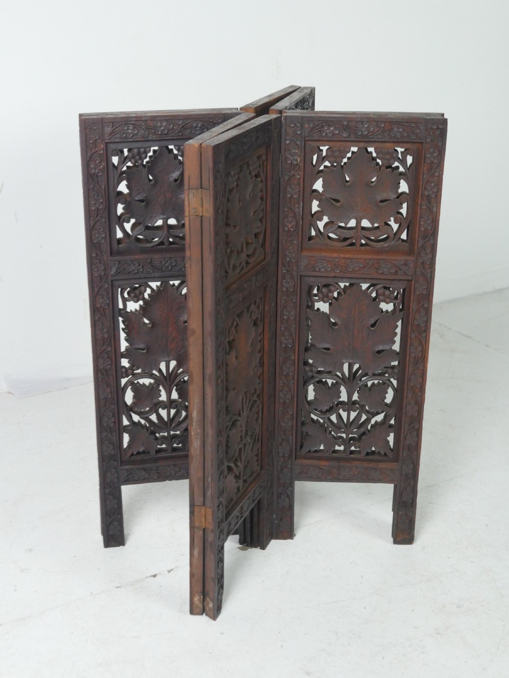An octagonal dark wood side table featuring hand-carved foliage fretwork on all side panels and a relief carved top. View X