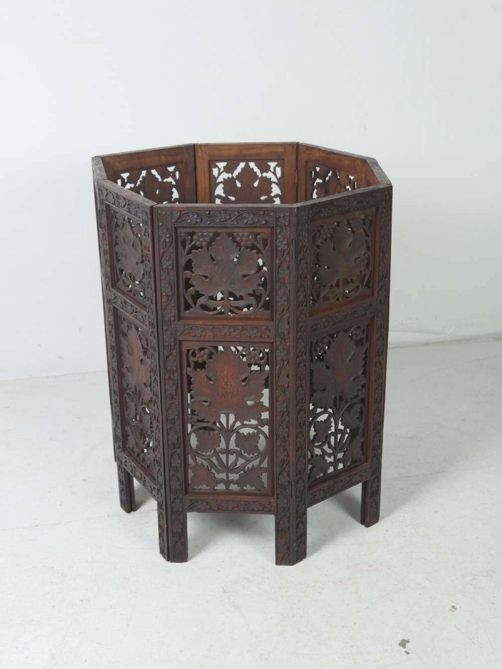 An octagonal dark wood side table featuring hand-carved foliage fretwork on all side panels and a relief carved top. View XI