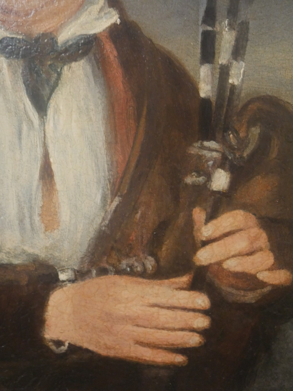 An oil portrait on canvas depicting a male Northumbrian piper holding smallpipes, housed in an ornate carved gilt frame. View III