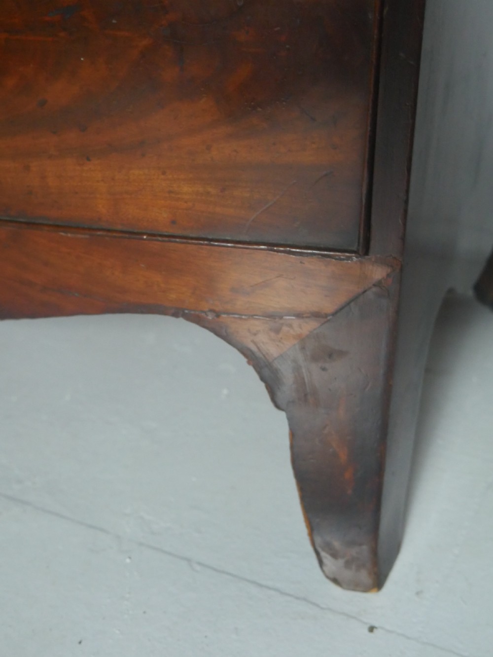 An early nineteenth-century mahogany bow-front chest of drawers featuring two short drawers over three long drawers with oval brass handles and splayed feet. View VIII