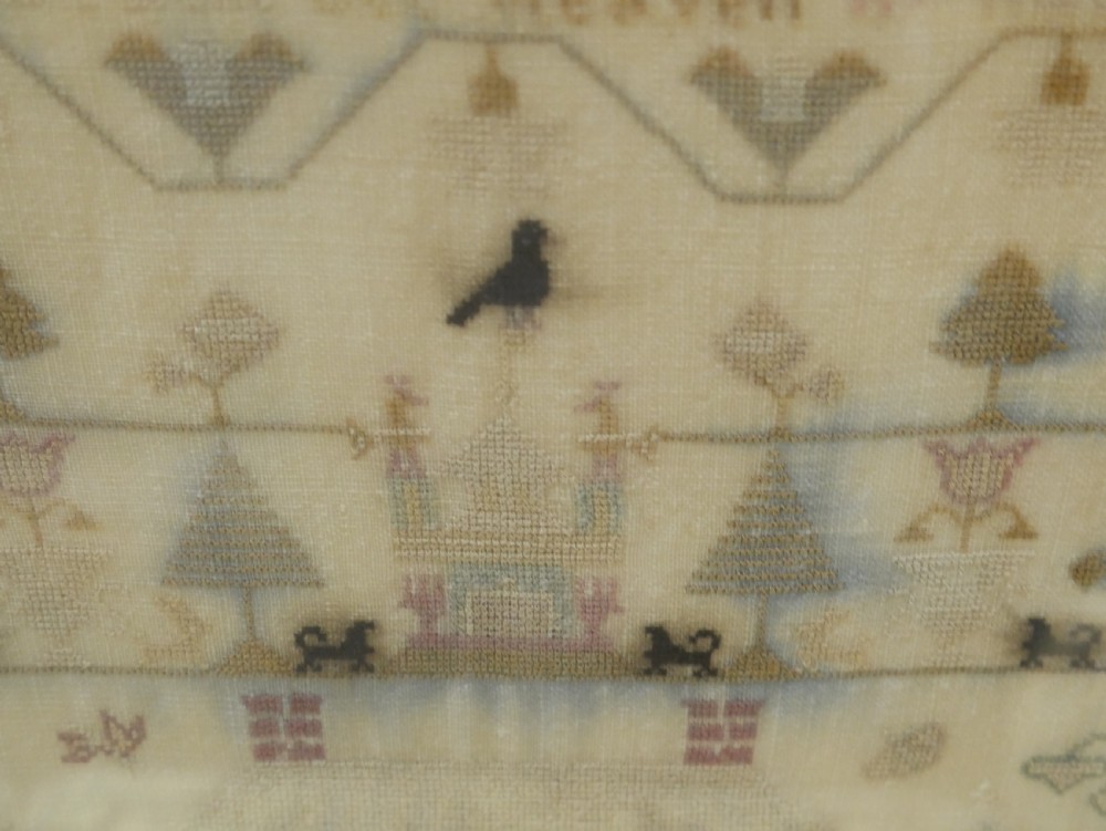 An 18th-century framed needlework sampler featuring a central brick house motif surrounded by trees, animals, figures, and stitched text on a linen ground. View VIII