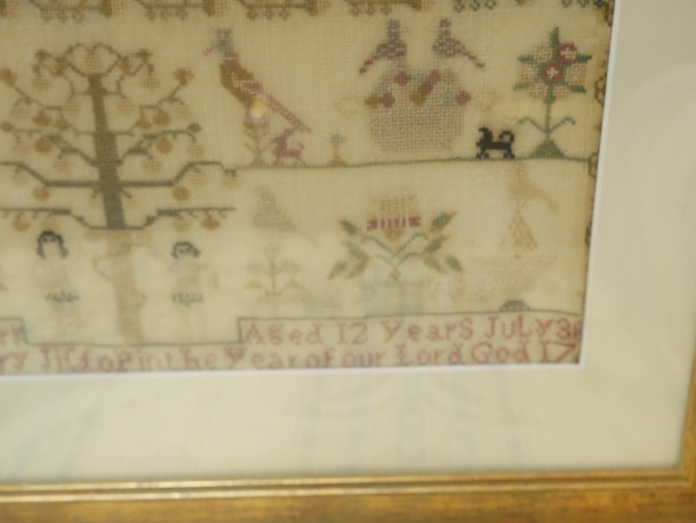 An 18th-century framed needlework sampler featuring a central brick house motif surrounded by trees, animals, figures, and stitched text on a linen ground. View X