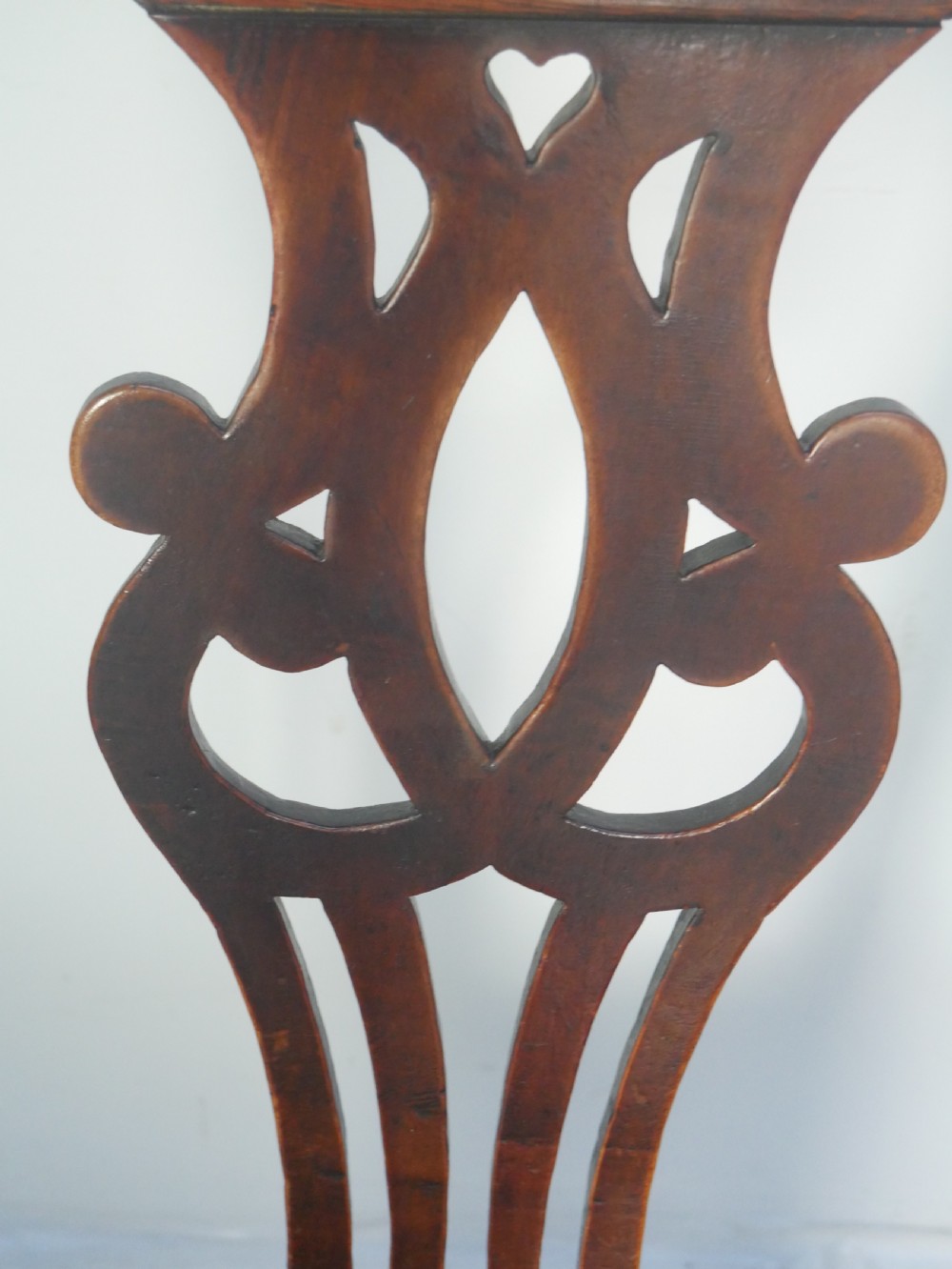 A dark wood Georgian country armchair featuring a pierced back splat with a heart motif, solid seat, curved armrests, and a sturdy stretcher base. View IV