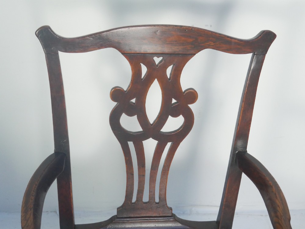 A dark wood Georgian country armchair featuring a pierced back splat with a heart motif, solid seat, curved armrests, and a sturdy stretcher base. View V