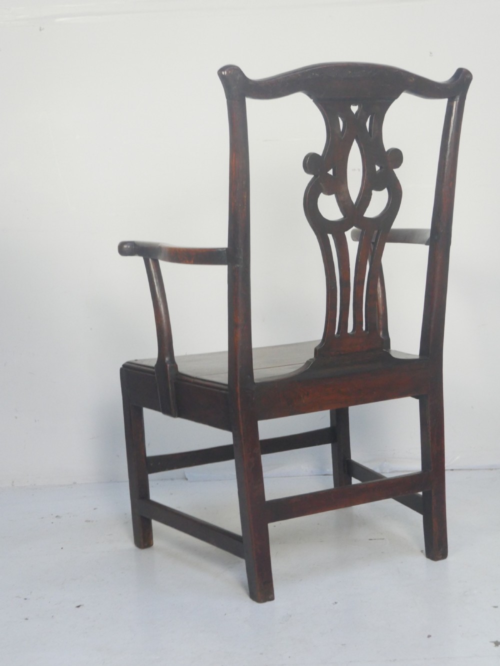 A dark wood Georgian country armchair featuring a pierced back splat with a heart motif, solid seat, curved armrests, and a sturdy stretcher base. View VII