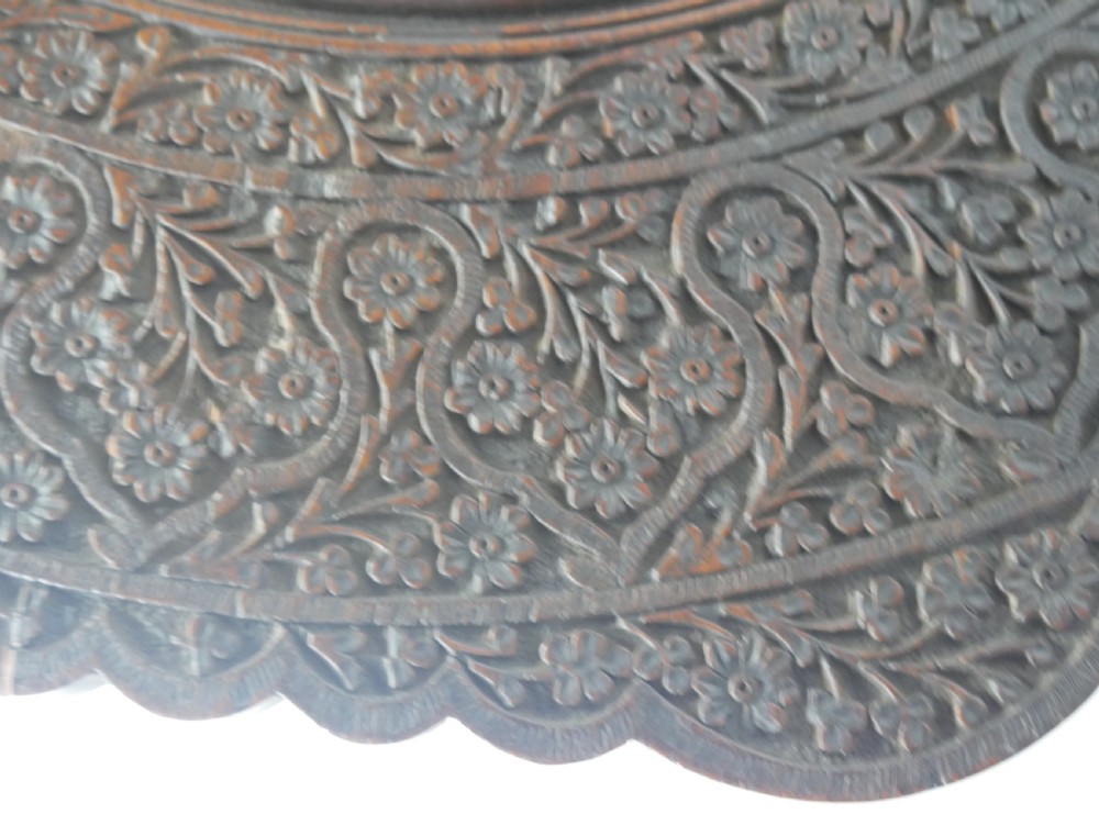 A dark hardwood octagonal side table featuring openwork fretwork panels carved with foliage motifs and a brass inlaid top surface. View V