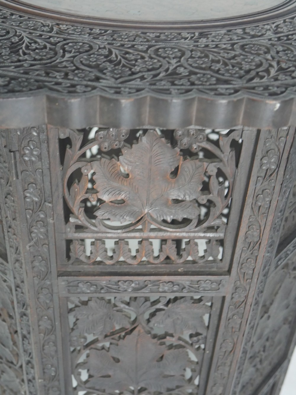 A dark hardwood octagonal side table featuring openwork fretwork panels carved with foliage motifs and a brass inlaid top surface. View VII