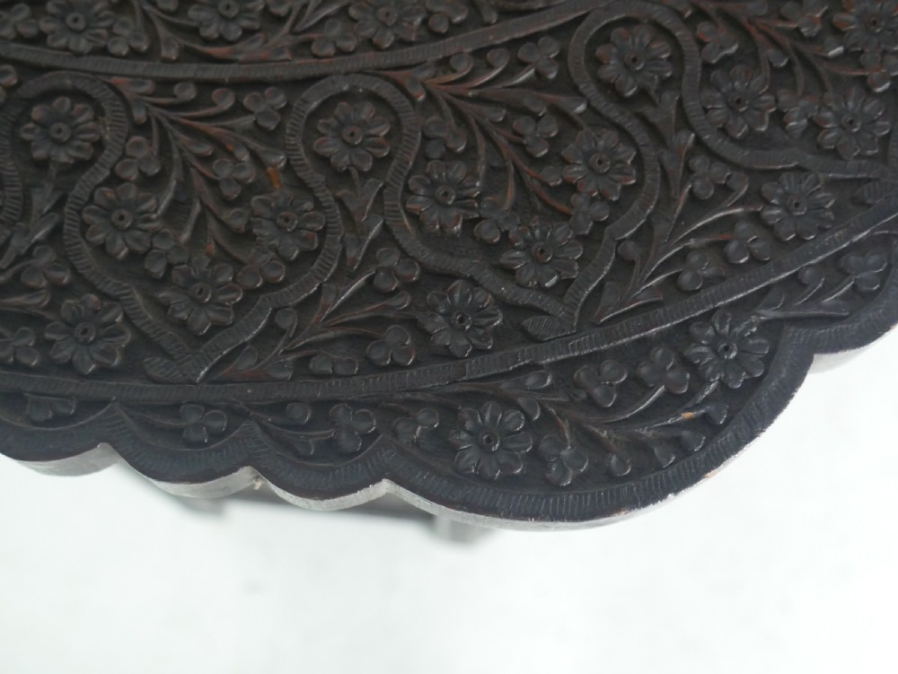 A dark hardwood octagonal side table featuring openwork fretwork panels carved with foliage motifs and a brass inlaid top surface. View VIII
