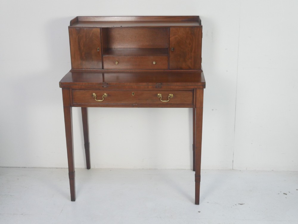 A mahogany bonheur de jour writing desk featuring a raised rear cabinet with two small doors and a central niche above a single frieze drawer on square tapered legs.