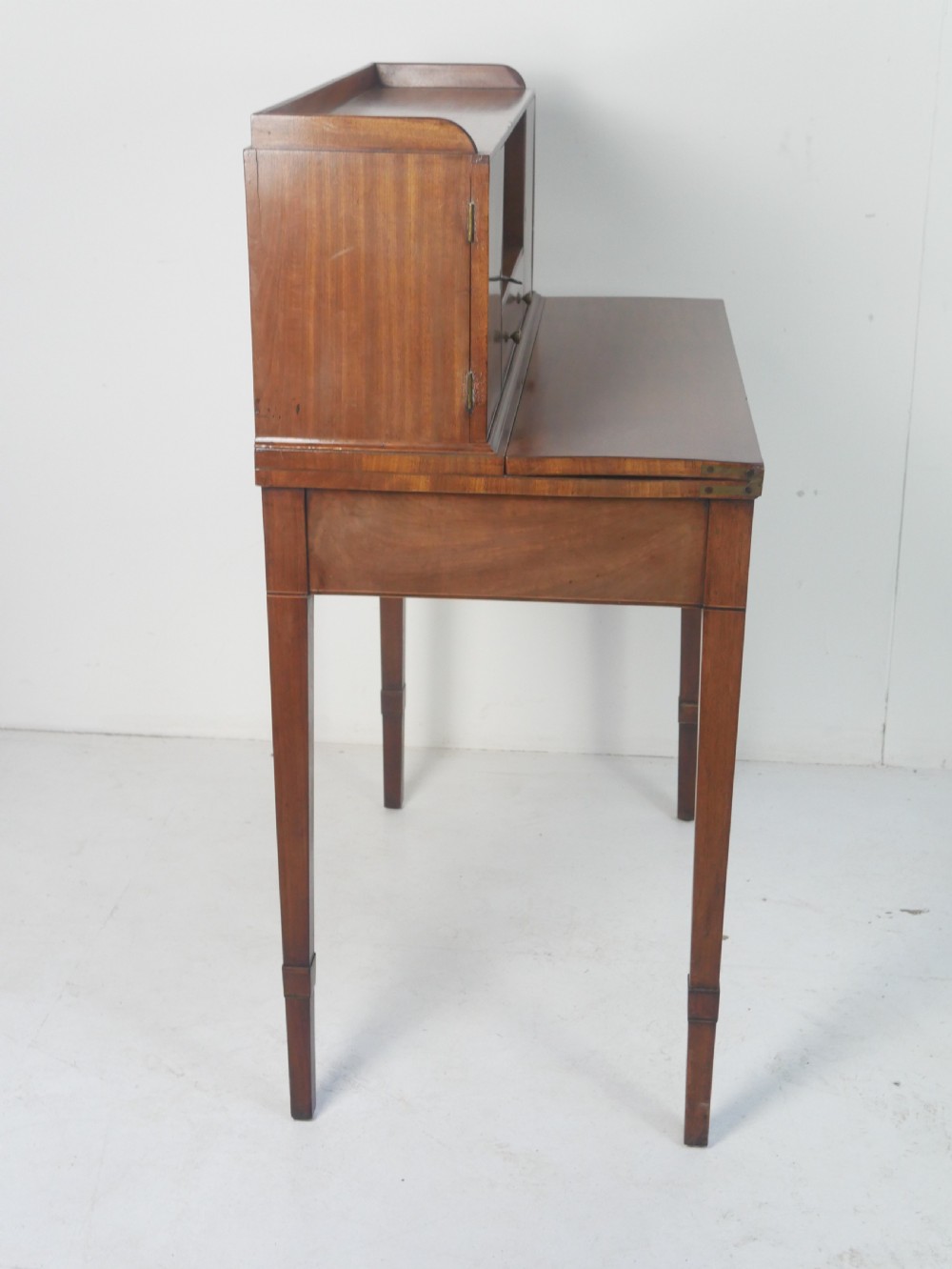 A mahogany bonheur de jour writing desk featuring a raised rear cabinet with two small doors and a central niche above a single frieze drawer on square tapered legs. View VII