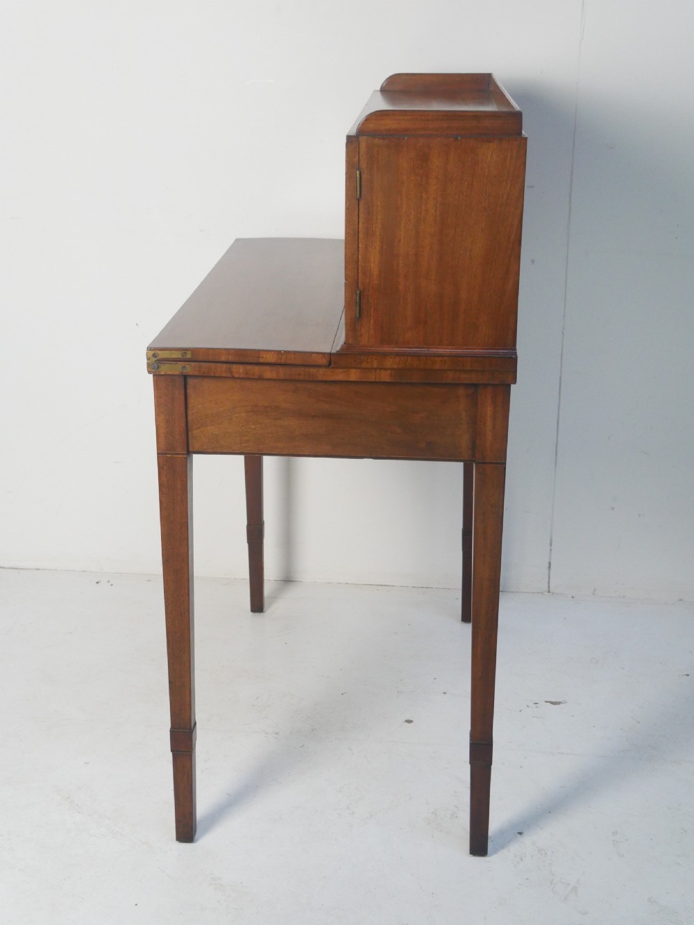 A mahogany bonheur de jour writing desk featuring a raised rear cabinet with two small doors and a central niche above a single frieze drawer on square tapered legs. View VIII