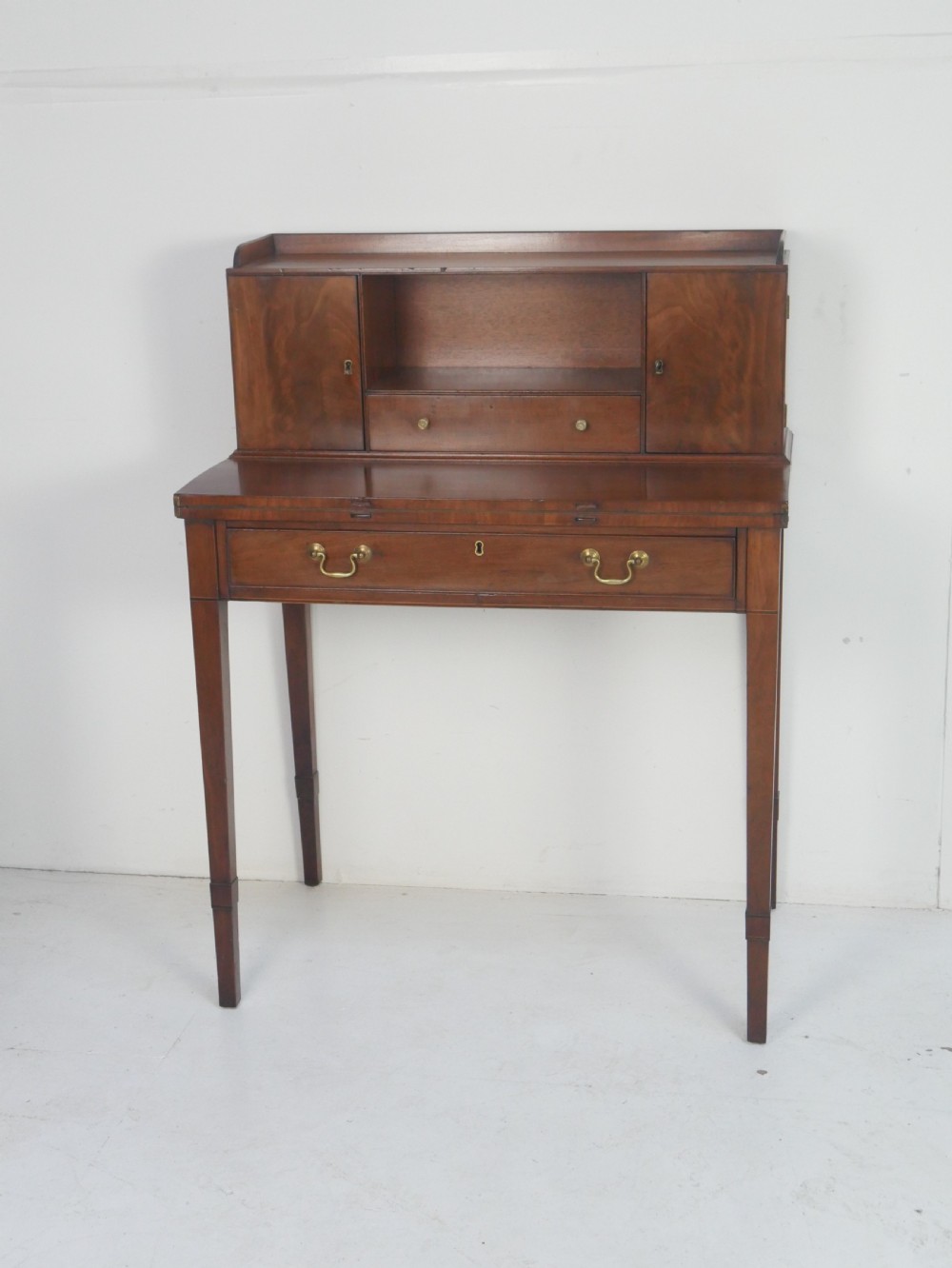 A mahogany bonheur de jour writing desk featuring a raised rear cabinet with two small doors and a central niche above a single frieze drawer on square tapered legs. View X