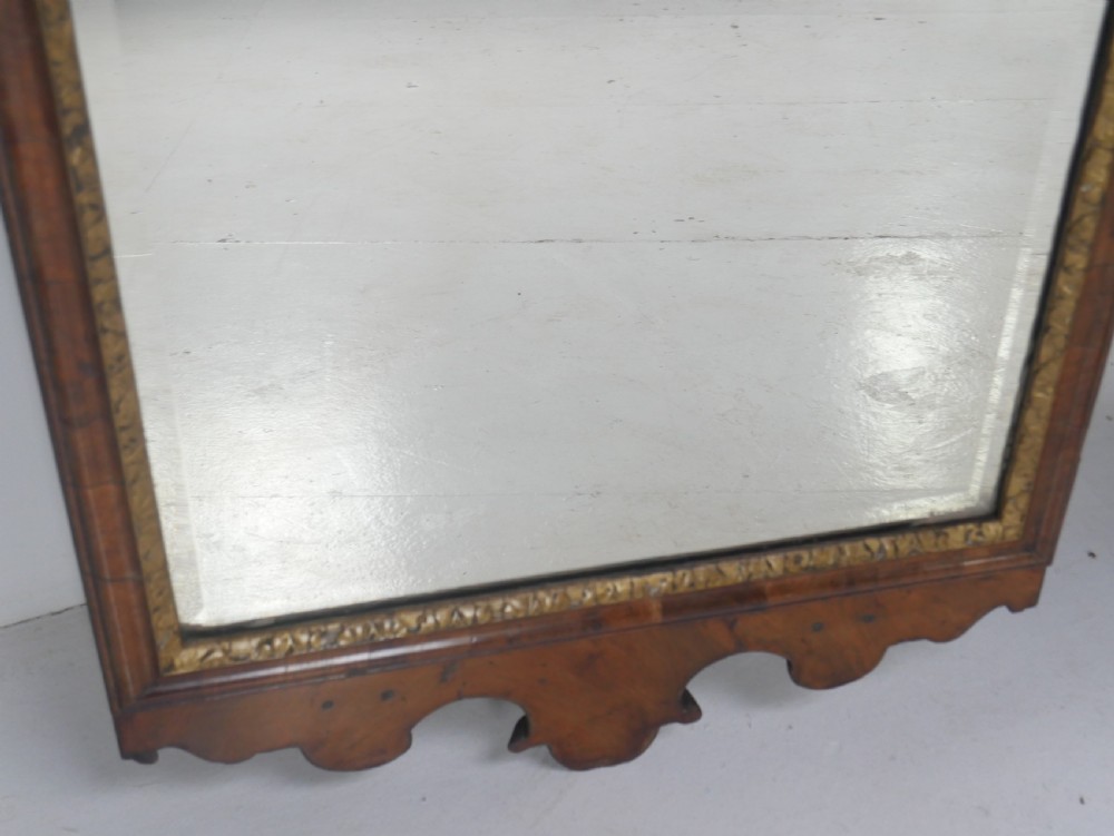 An 18th-century walnut wall mirror featuring a scroll-carved crest and apron, rounded upper corners, and a gilded inner moulding frame. View III