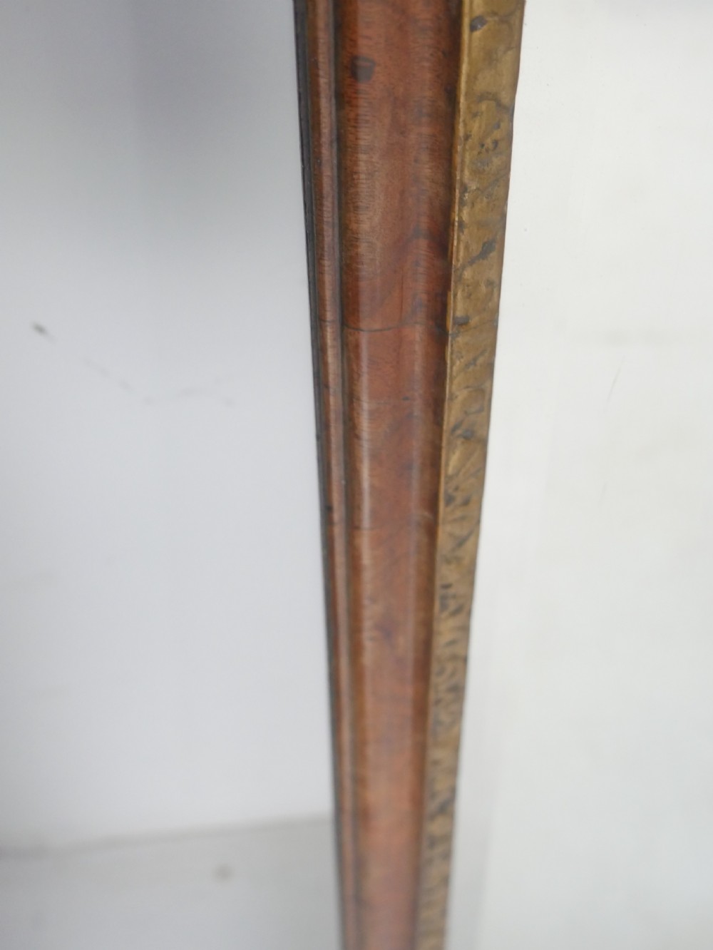An 18th-century walnut wall mirror featuring a scroll-carved crest and apron, rounded upper corners, and a gilded inner moulding frame. View VII