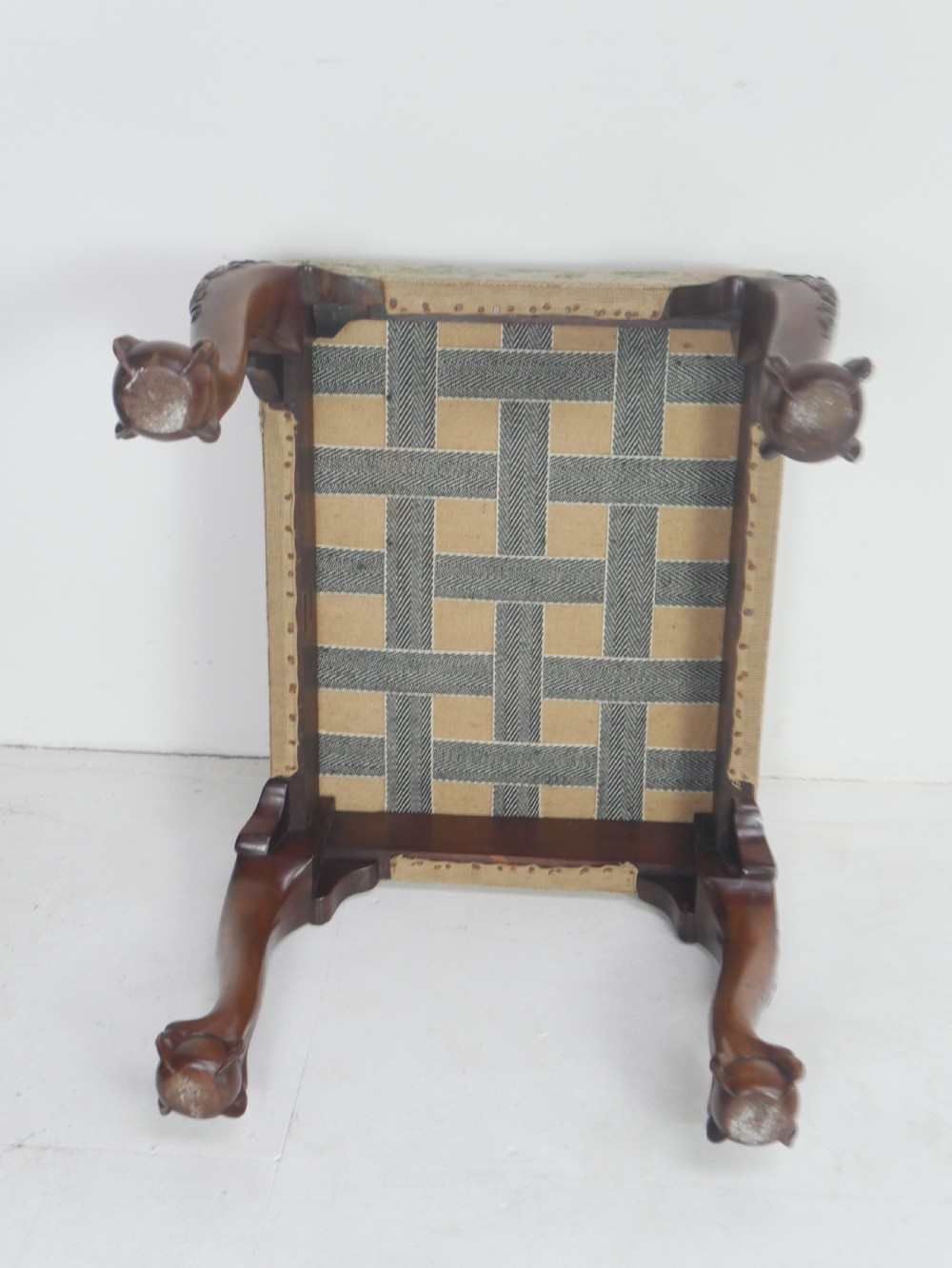 A square upholstered footstool featuring floral needlepoint fabric, carved cabriole legs, and claw and ball feet. View VI