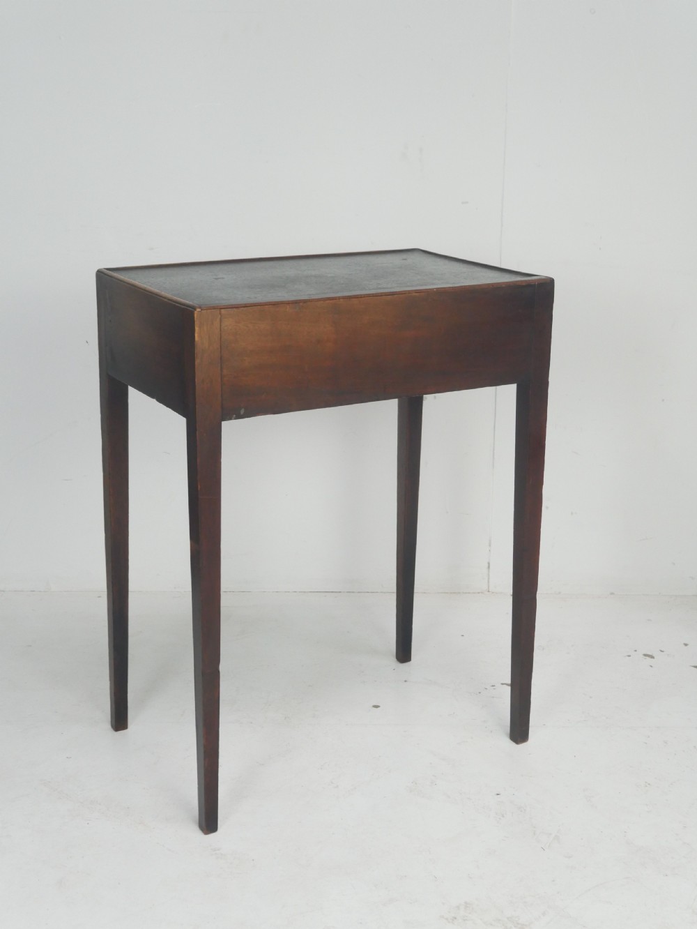 A Georgian mahogany side table featuring a dark leather inset top, frieze drawer with brass handles, and slender tapered legs. View II