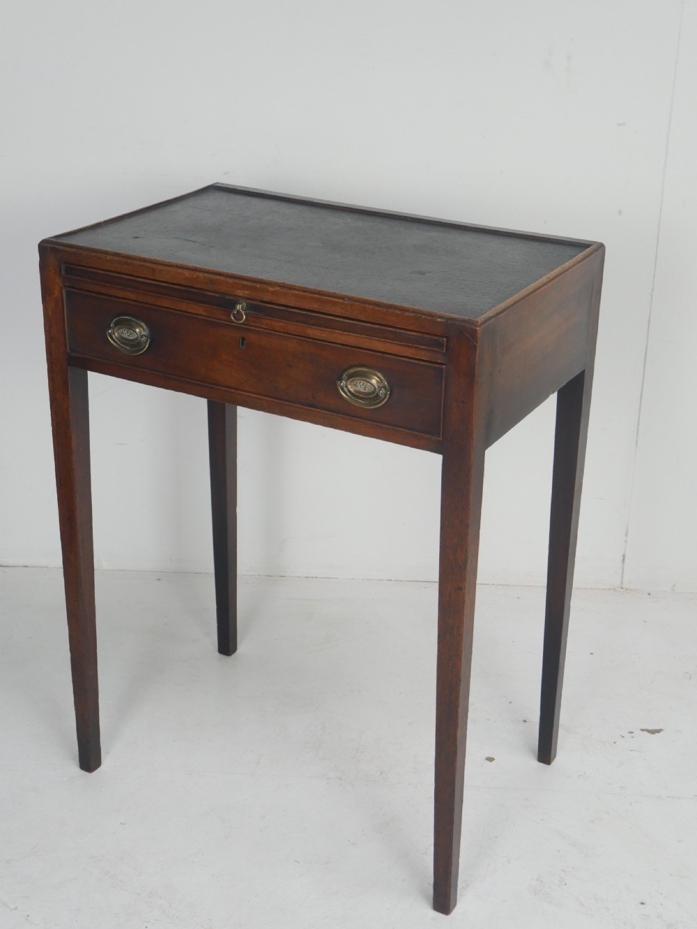 A Georgian mahogany side table featuring a dark leather inset top, frieze drawer with brass handles, and slender tapered legs. View VI