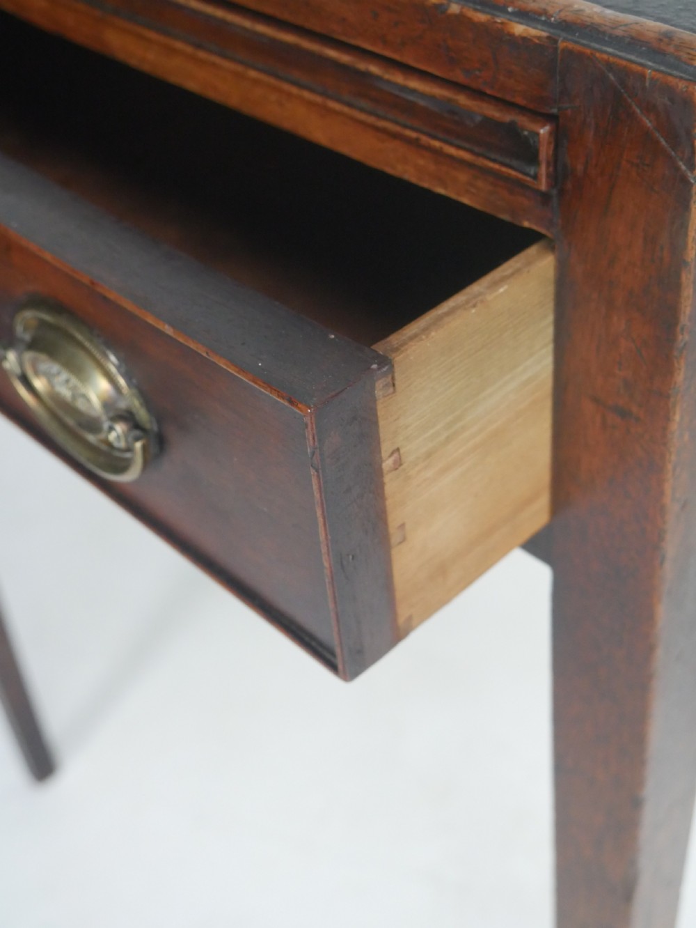 A Georgian mahogany side table featuring a dark leather inset top, frieze drawer with brass handles, and slender tapered legs. View VII