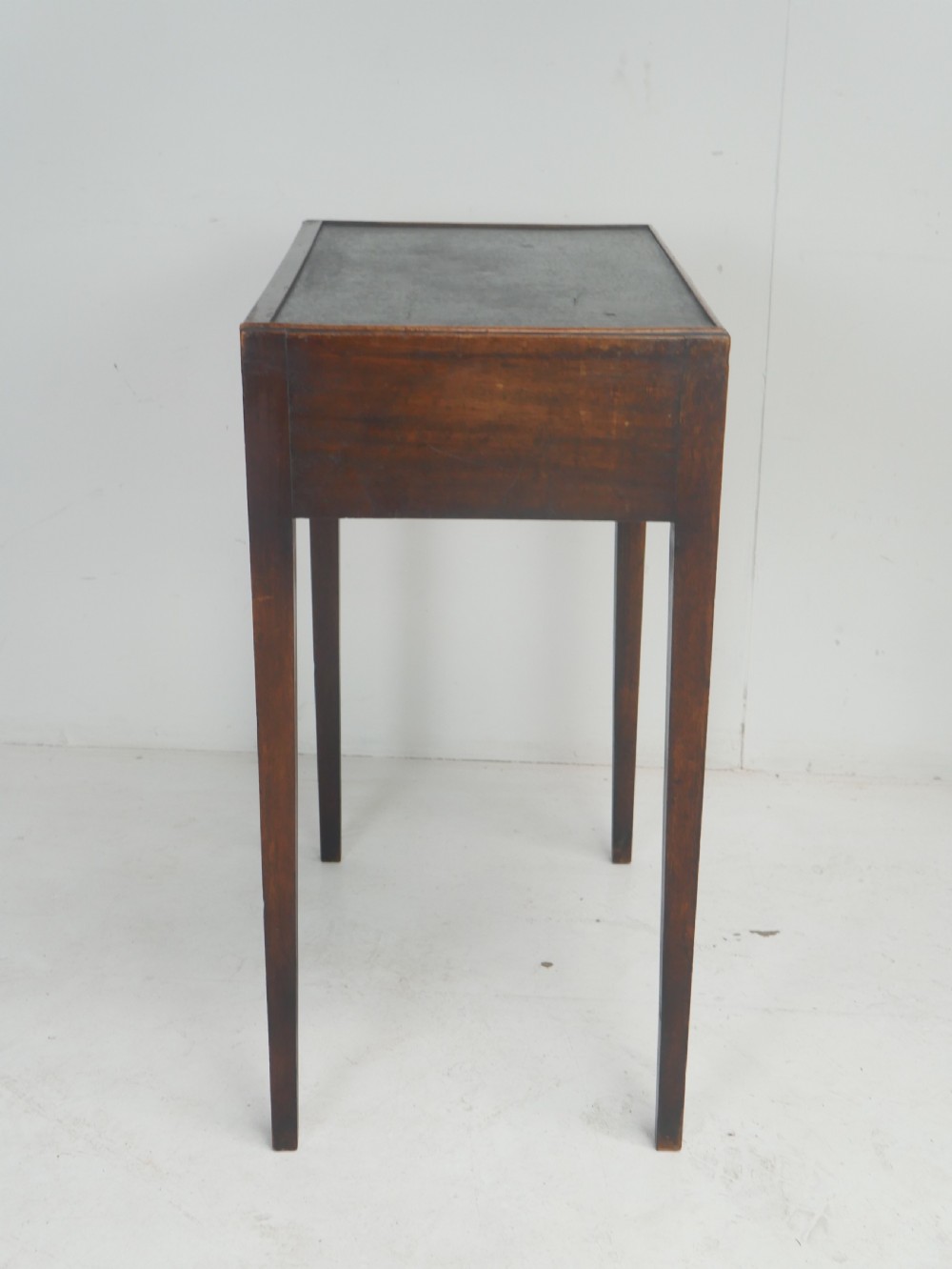 A Georgian mahogany side table featuring a dark leather inset top, frieze drawer with brass handles, and slender tapered legs. View XI