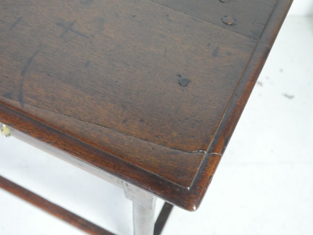 A dark brown Georgian oak side table featuring a single drawer with brass drop handles, turned legs, and a sturdy lower perimeter stretcher. View VII