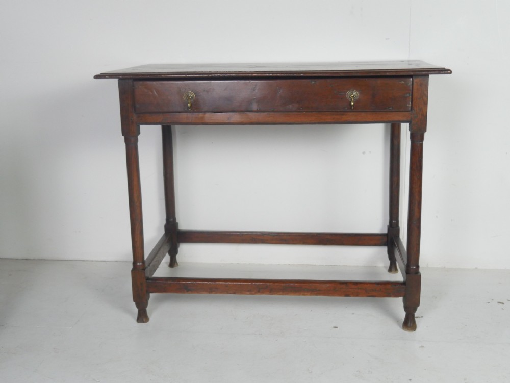 A dark brown Georgian oak side table featuring a single drawer with brass drop handles, turned legs, and a sturdy lower perimeter stretcher. View IX
