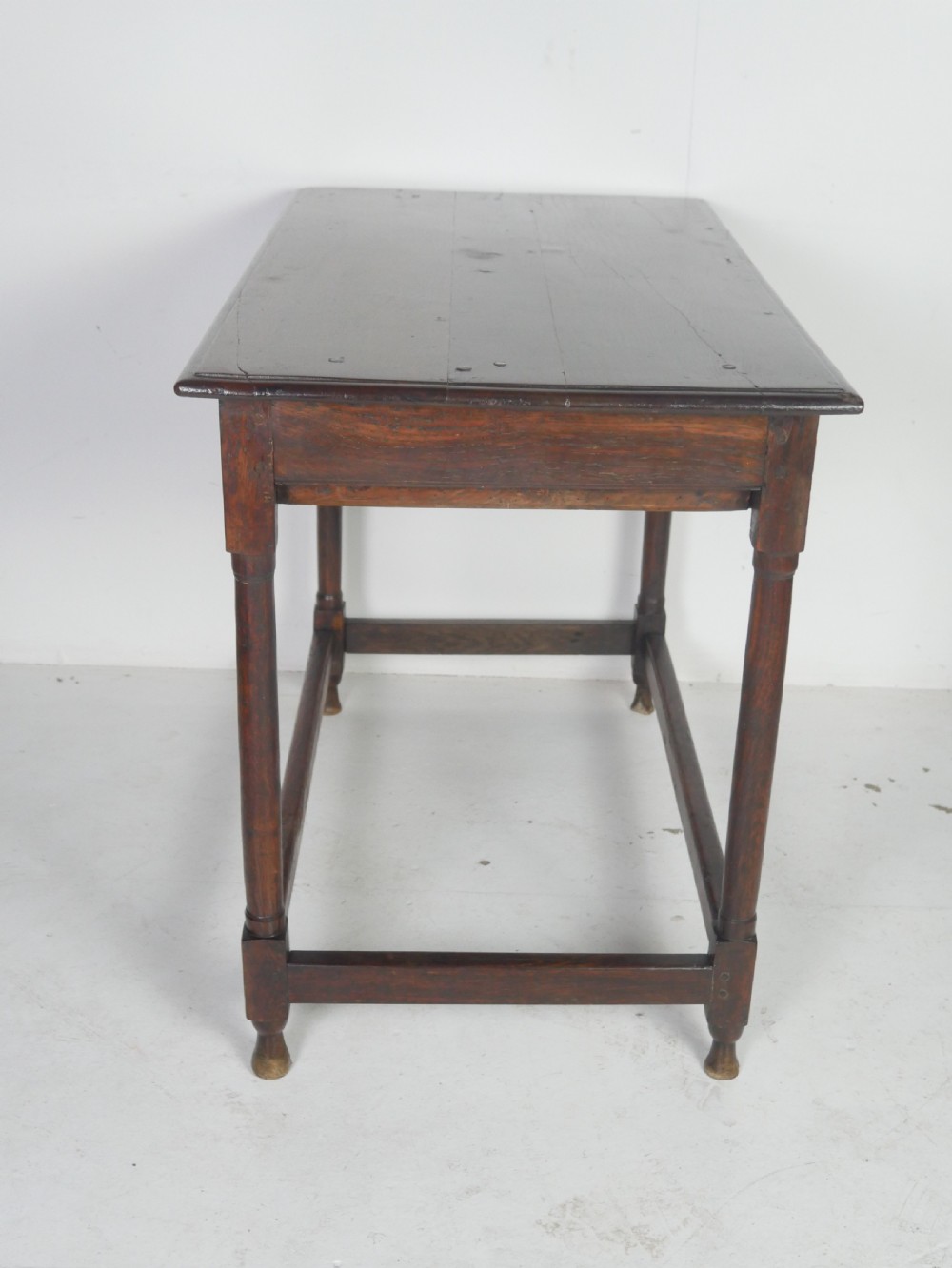 A dark brown Georgian oak side table featuring a single drawer with brass drop handles, turned legs, and a sturdy lower perimeter stretcher. View X