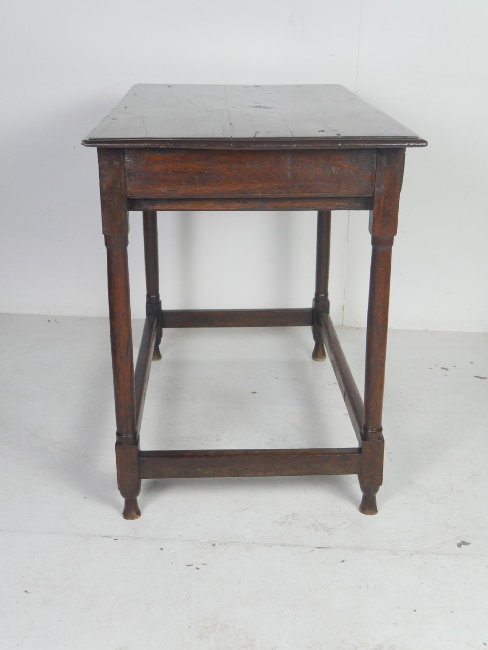 A dark brown Georgian oak side table featuring a single drawer with brass drop handles, turned legs, and a sturdy lower perimeter stretcher. View XII