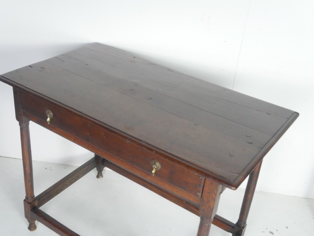 A dark brown Georgian oak side table featuring a single drawer with brass drop handles, turned legs, and a sturdy lower perimeter stretcher. View XV
