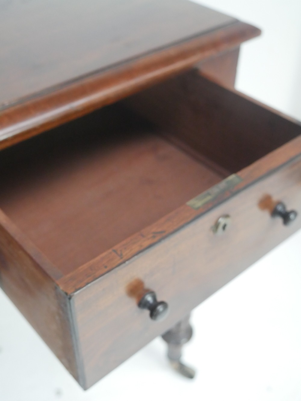 An English Regency mahogany freestanding writing desk featuring three frieze drawers with small turned knobs, supported by four reeded legs on brass castors. View VII