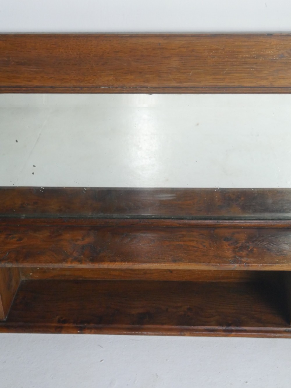 A rectangular antique oak hall mirror featuring a moulded wooden frame, central reflective glass, and an integrated lower display shelf with small cubby compartments. View II