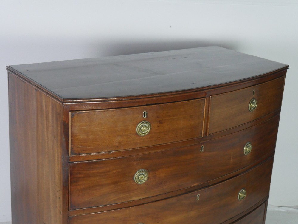 A Georgian mahogany bow-front chest of drawers featuring two short drawers over three long graduated drawers with circular brass drop handles. View IX