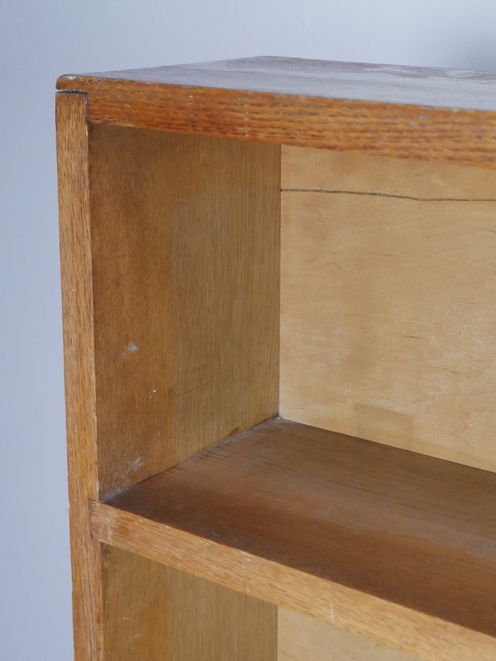 A wide wooden open bookcase made of light oak with four horizontal shelves and a simple plinth base. View II
