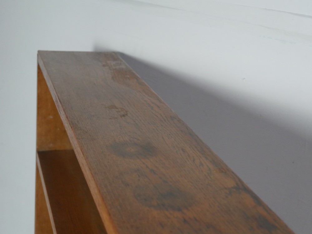 A wide wooden open bookcase made of light oak with four horizontal shelves and a simple plinth base. View V