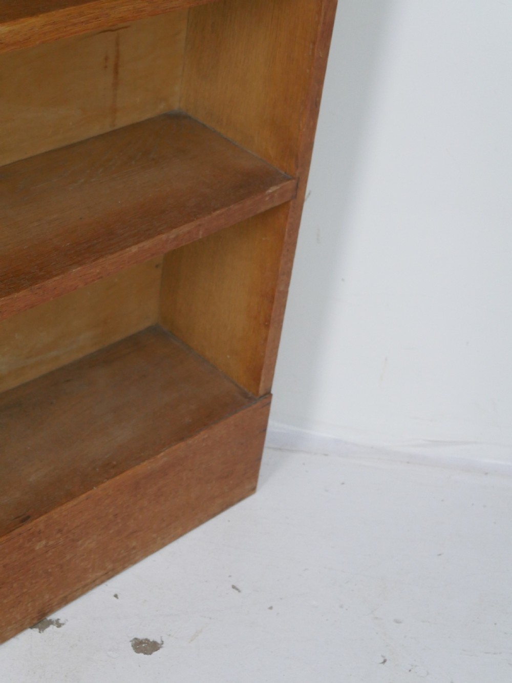 A wide wooden open bookcase made of light oak with four horizontal shelves and a simple plinth base. View VIII