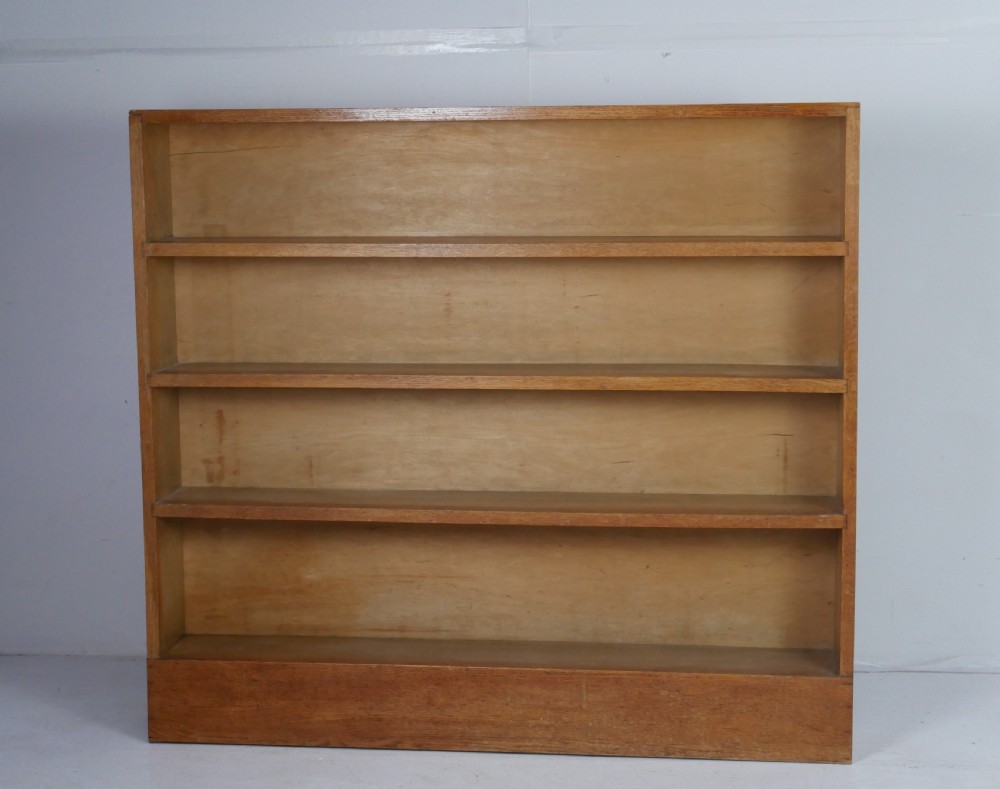 A wide wooden open bookcase made of light oak with four horizontal shelves and a simple plinth base. View XI