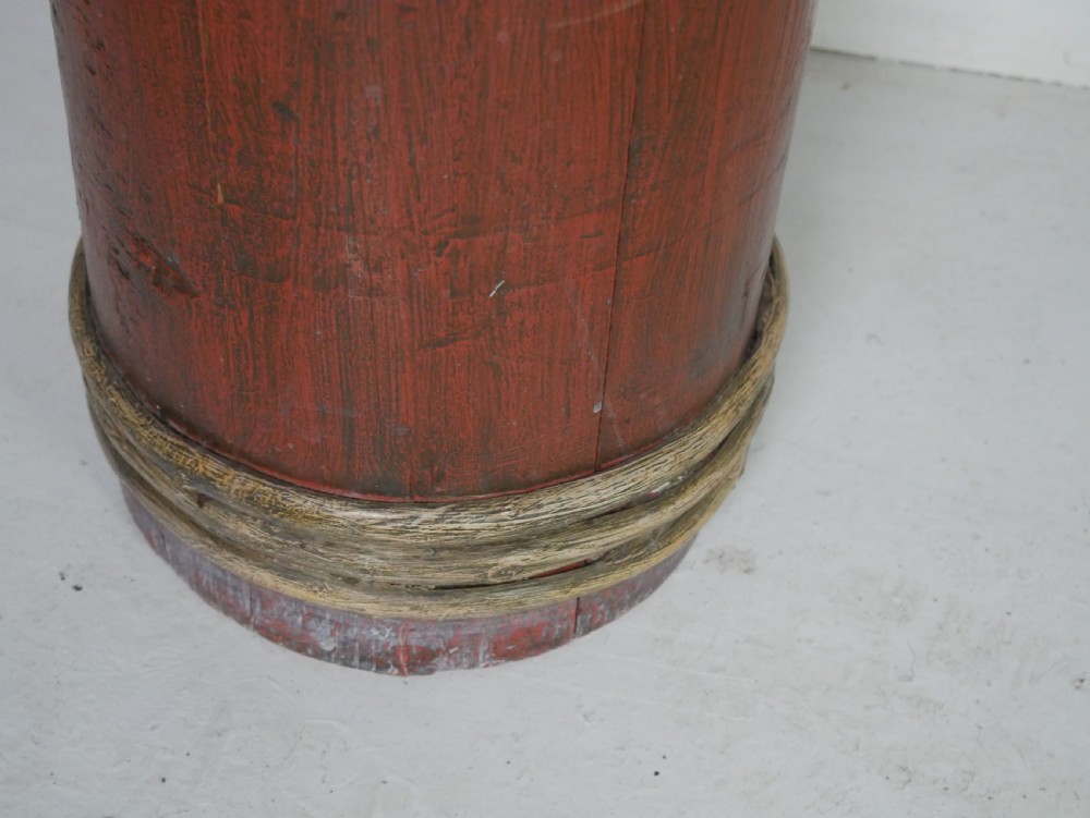 A tall, cylindrical red-painted wooden umbrella stand featuring hand-painted floral motifs and raised wooden banding. View V