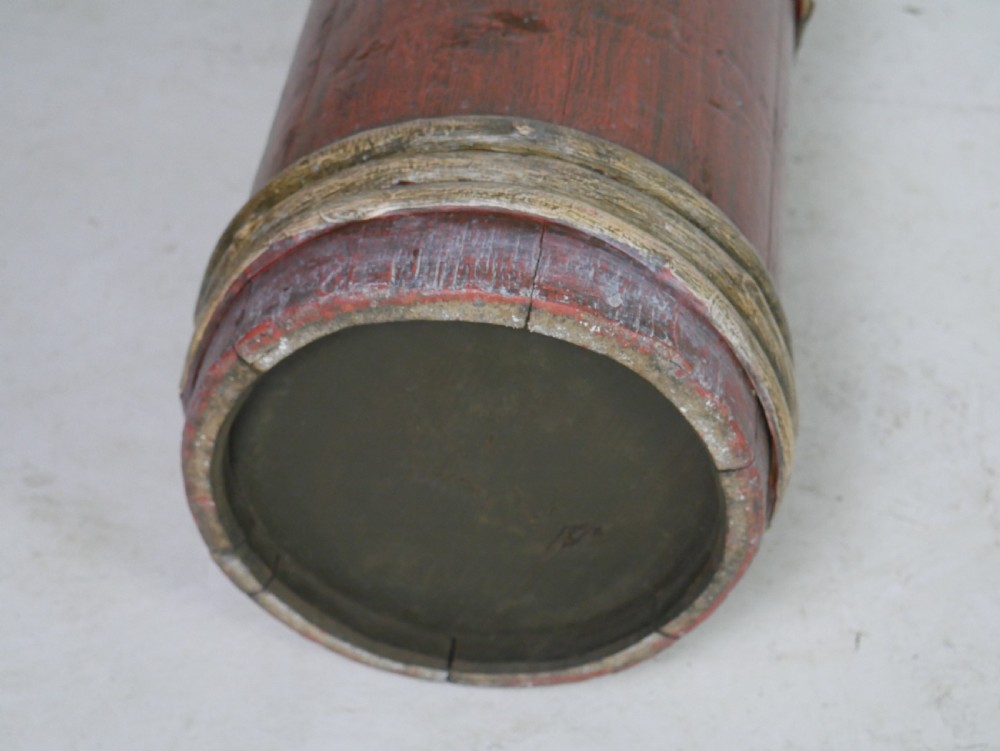 A tall, cylindrical red-painted wooden umbrella stand featuring hand-painted floral motifs and raised wooden banding. View VII