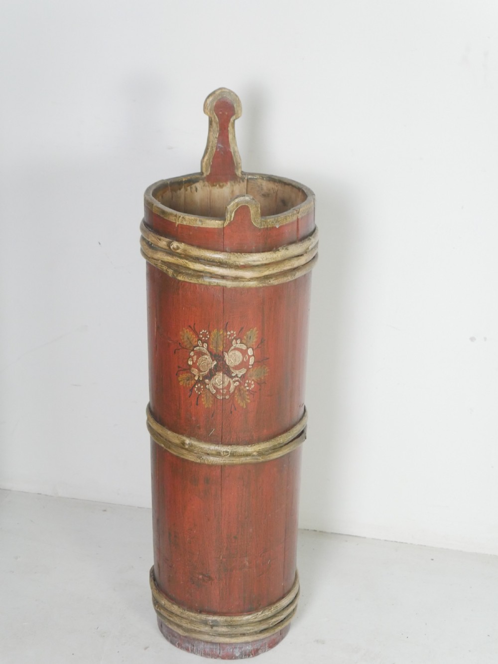 A tall, cylindrical red-painted wooden umbrella stand featuring hand-painted floral motifs and raised wooden banding. View XI