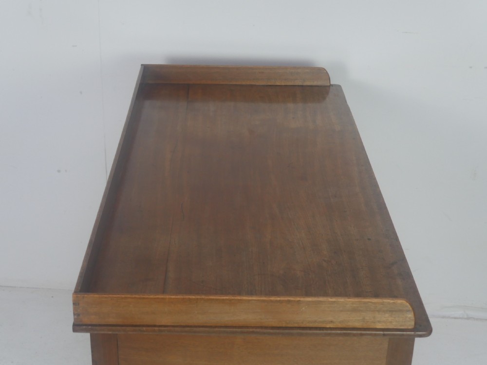 A Regency period mahogany writing desk featuring a low rear gallery, five drawers with brass handles, and four turned legs. View II