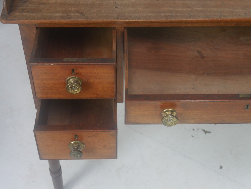 A Regency period mahogany writing desk featuring a low rear gallery, five drawers with brass handles, and four turned legs. View VII