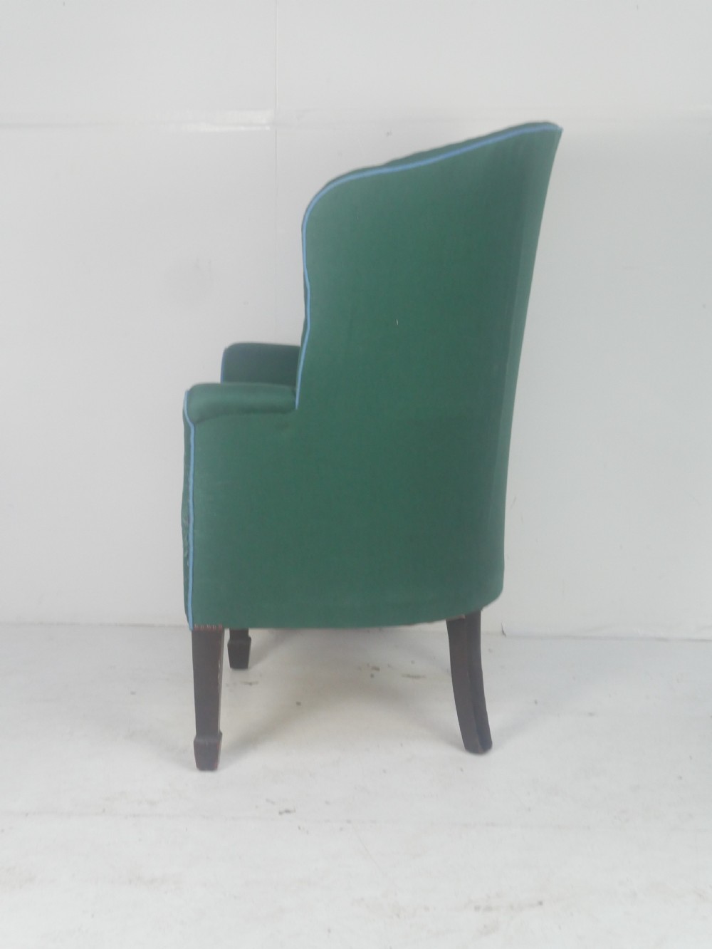 A forest green upholstered barrel back armchair with vertical channel tufting, light blue contrast piping, and dark tapered square legs. View III