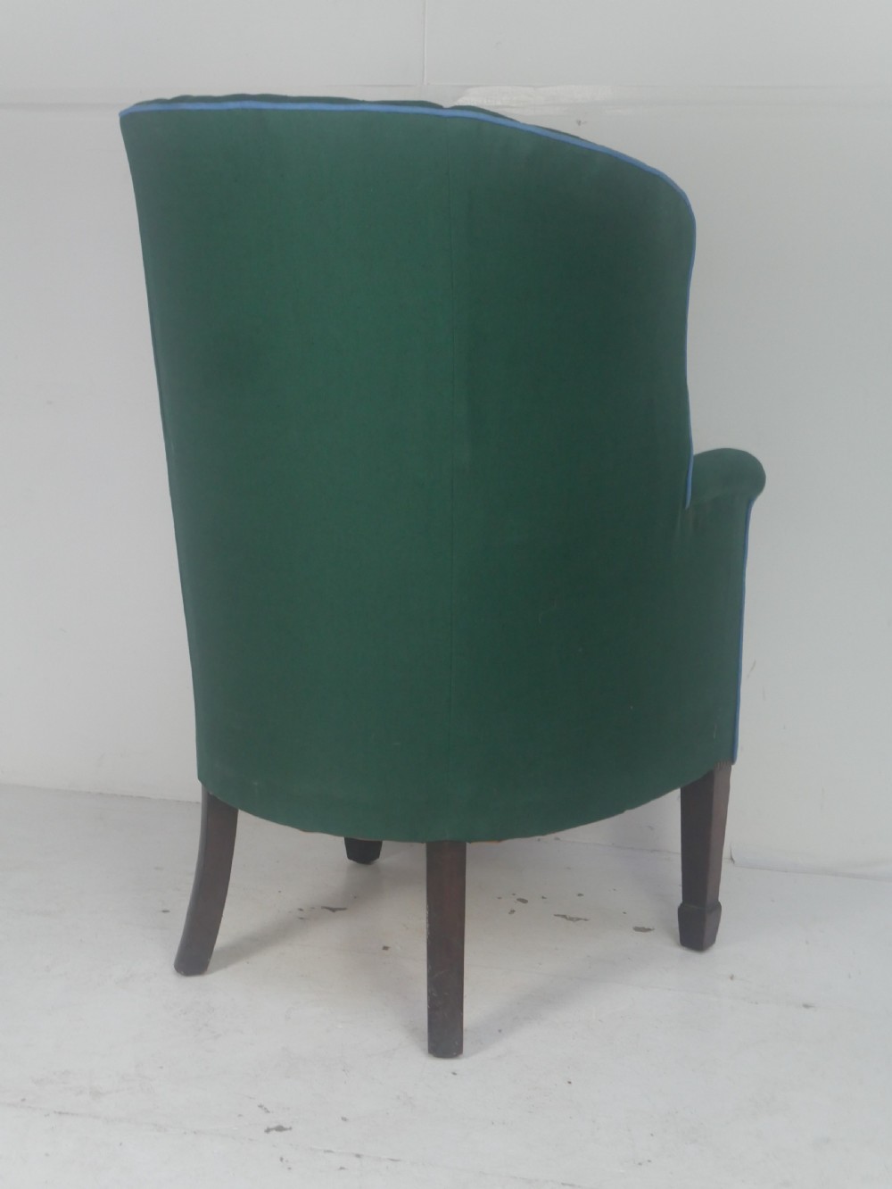 A forest green upholstered barrel back armchair with vertical channel tufting, light blue contrast piping, and dark tapered square legs. View VI