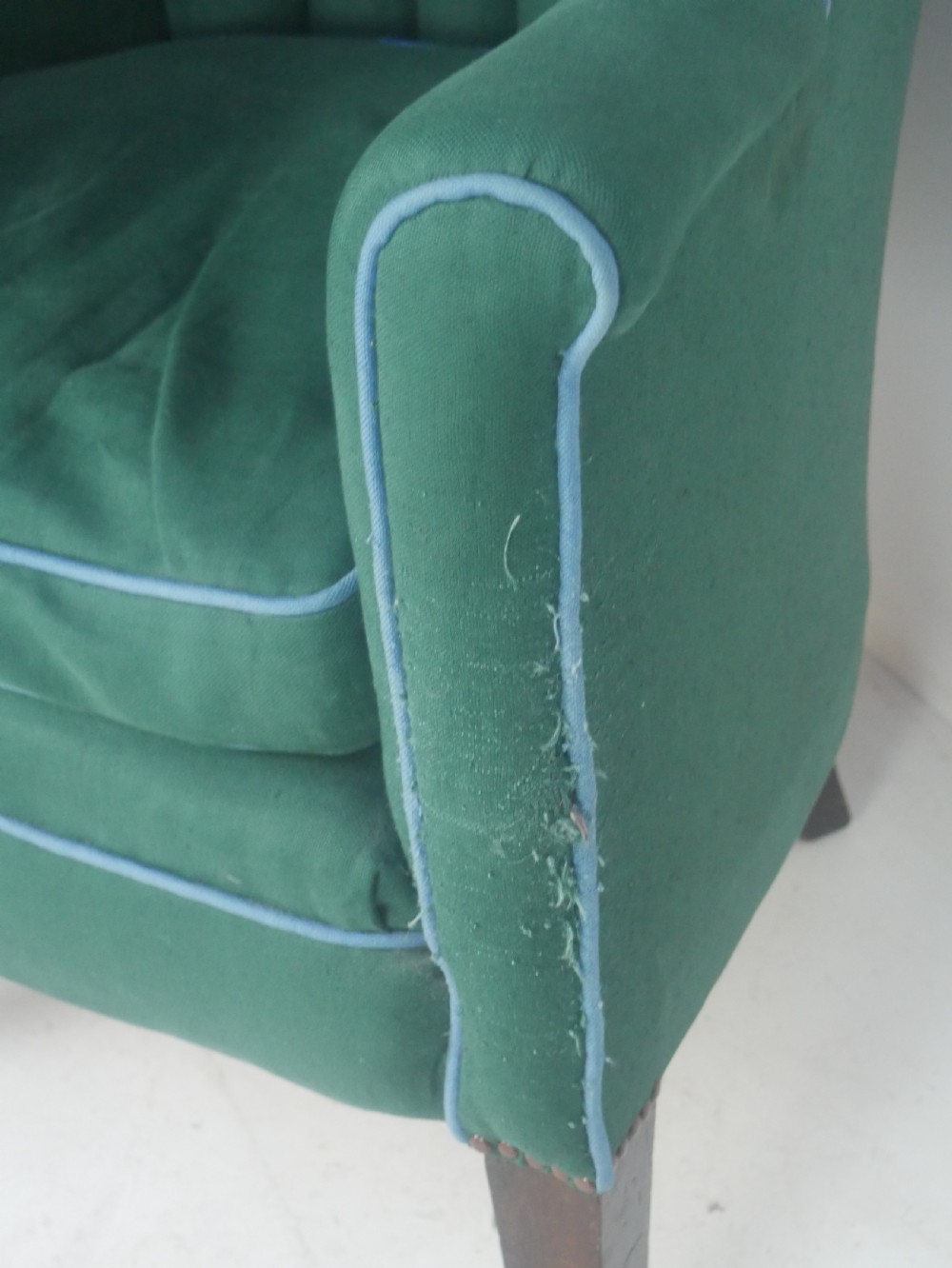 A forest green upholstered barrel back armchair with vertical channel tufting, light blue contrast piping, and dark tapered square legs. View IX